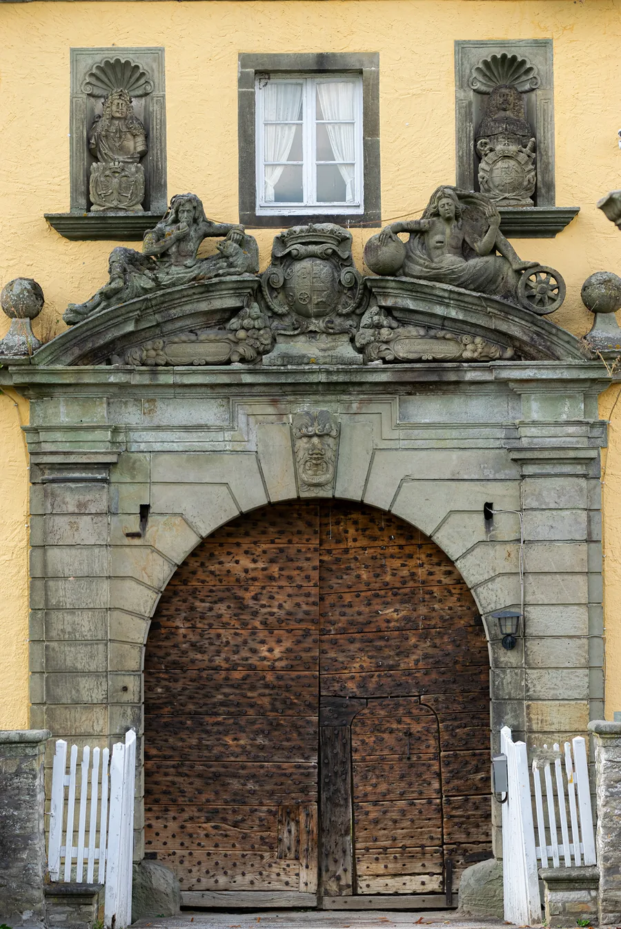 Das barocke Portal des Schlosses mit Wappenaufsatz über dem hölzernen Torflügel