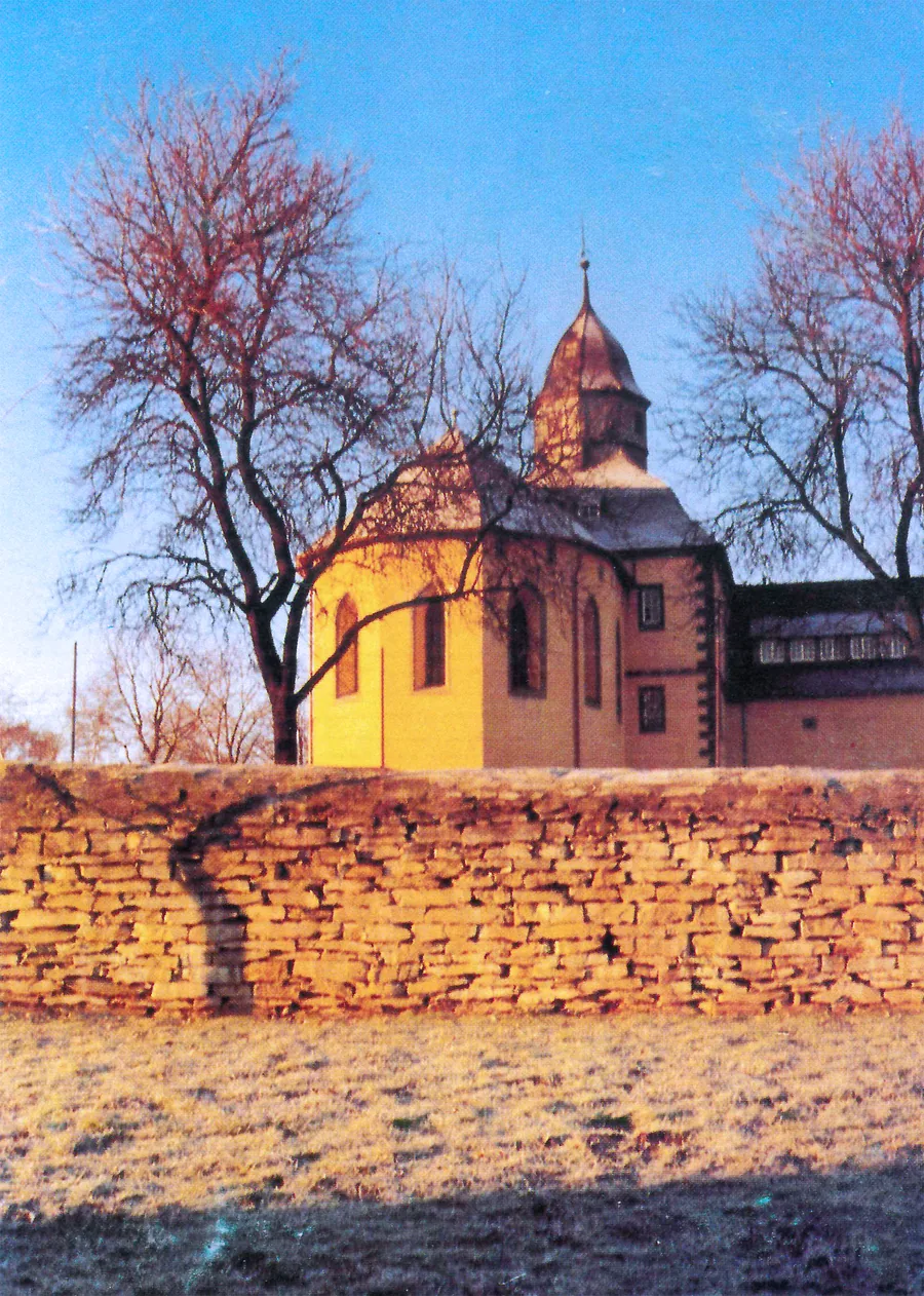 Die Schlosskapelle im Abendlicht, davor eine Bruchsteinmauer